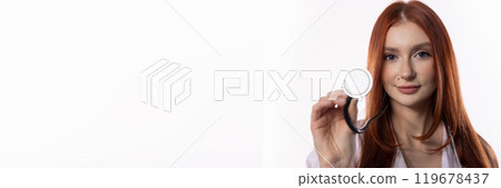 A young female doctor is holding a stethoscope while working in a professional medical setting 119678437