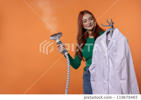 A Woman Skillfully Using a Garment Steamer on a Crisp White Shirt for a Smooth Finish A Woman Skillfully Using a Garment Steamer on a Crisp White Shirt for a Smooth Finish 119678465