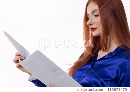 A Confident Woman in a Stylish Blue Shirt is Reviewing Important Documents at Work 119678479