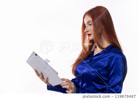 A Professional Woman Dressed in a Blue Satin Top Engaged in Reading a Document at Work A Professional Woman Dressed in a Blue Satin Top Engaged in Reading a Document at Work 119678487