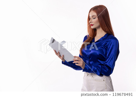 A Confident Young Woman Reviewing an Important Document in a Stylish Blue Satin Shirt A Confident Young Woman Reviewing an Important Document in a Stylish Blue Satin Shirt 119678491