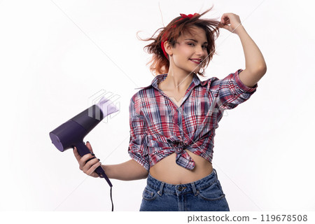 A young woman joyfully having fun while playfully using a hair dryer at home or in a salon A young woman joyfully having fun while playfully using a hair dryer at home or in a salon 119678508