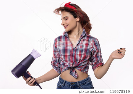 A Cheerful Woman Happily Using a Hair Dryer While Dressed in a Fun Retro Style Outfit A Cheerful Woman Happily Using a Hair Dryer While Dressed in a Fun Retro Style Outfit 119678519