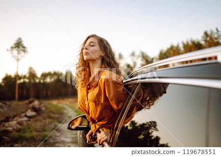 Happy woman on summer trip, travels leaning out of the car window. Active lifestyle. Travel concept. Happy woman on summer trip, travels leaning out of the car window. Active lifestyle. Travel concept. 119678551