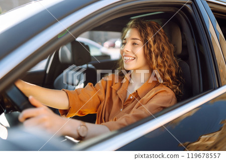 Smiling woman driving a car. Young traveler driving. Car travel, lifestyle concept. 119678557