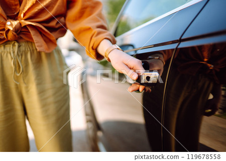 Close-up of a woman's hand opening a car door, keyless entry, outdoors. Transport, travel concept. 119678558