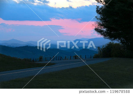 Scenic mountain road at twilight with colorful sunset sky Scenic mountain road at twilight with colorful sunset sky 119678588