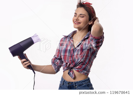 A woman is joyfully using a retrostyle hair dryer, showcasing her vibrant personality 119678641