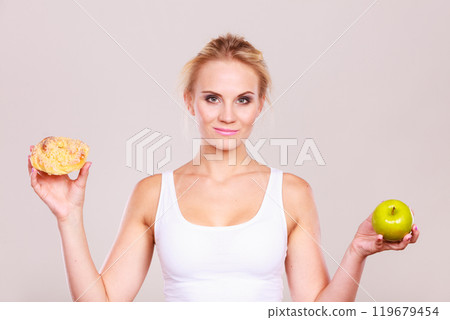 Woman holds cake and fruit in hand choosing Woman holds cake and fruit in hand choosing 119679454