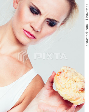 undecided woman holds cake sweet bun in hand undecided woman holds cake sweet bun in hand 119679455