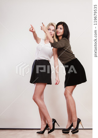 Two fashion women pointing wit finger Two fashion women pointing wit finger 119679535