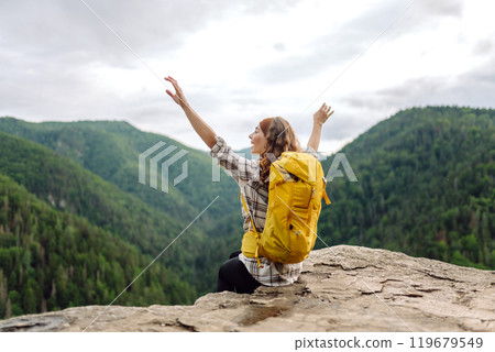 An active woman with a yellow backpack travels through the mountains. Travel concept. 119679549