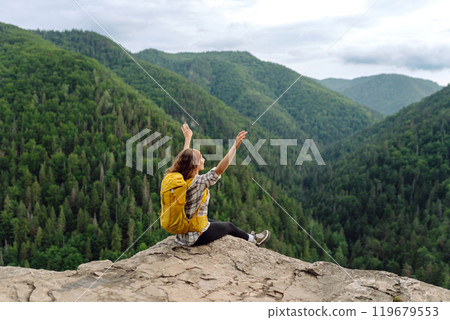 An active woman with a yellow backpack travels through the mountains. Travel concept. An active woman with a yellow backpack travels through the mountains. Travel concept. 119679553