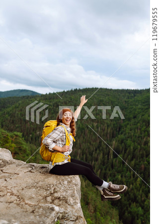 An active woman with a yellow backpack travels through the mountains. Travel concept. An active woman with a yellow backpack travels through the mountains. Travel concept. 119679555