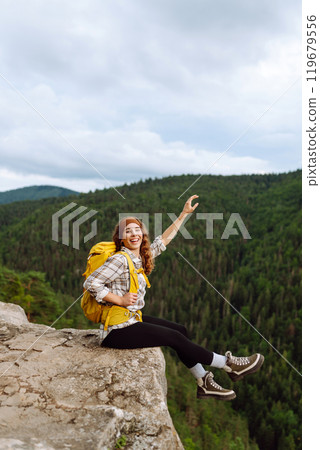 An active woman with a yellow backpack travels through the mountains. Travel concept. An active woman with a yellow backpack travels through the mountains. Travel concept. 119679556