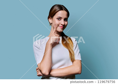 Portrait of beautiful young girl with long red hair looking at camera on blue background Portrait of beautiful young girl with long red hair looking at camera on blue background 119679756