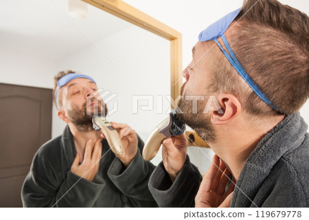 Man shaving trimming his beard Man shaving trimming his beard 119679778