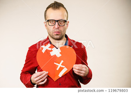Sad adult man holding broken heart 119679803