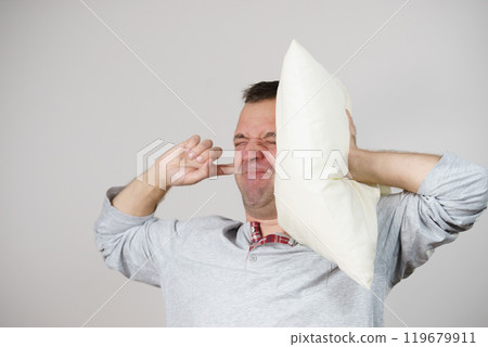 Sleepy man with pillow closing his ear Sleepy man with pillow closing his ear 119679911