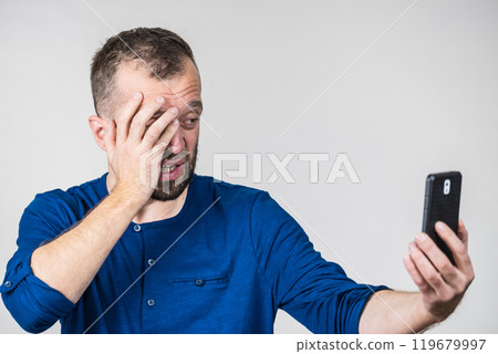 Worried adult man looking at smartphone Worried adult man looking at smartphone 119679997