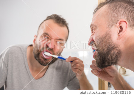 Man brushing his teeth in bathroom Man brushing his teeth in bathroom 119680156