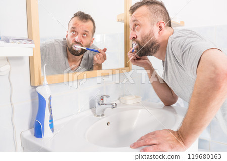 Man brushing his teeth in bathroom 119680163