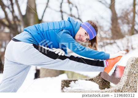 Woman wearing sportswear exercising outside during winter 119680312