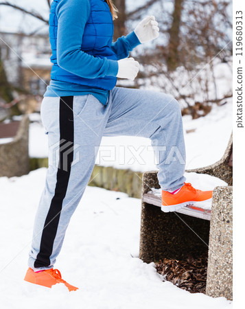 Woman wearing sportswear exercising outside during winter 119680313