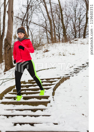 Woman wearing sportswear exercising outside during winter Woman wearing sportswear exercising outside during winter 119680351