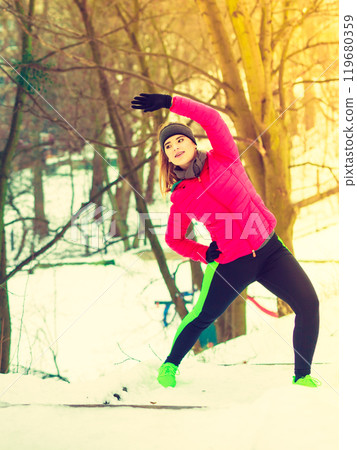 Woman wearing sportswear exercising outside during winter Woman wearing sportswear exercising outside during winter 119680359