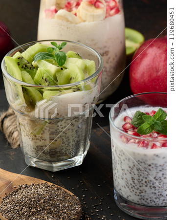 Chia seed glasses filled with yogurt and decorated with fresh fruit pieces on the table, healthy breakfast. 119680451