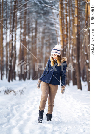 Portrait of beautiful girl with long hair, in a blue jacket. Fashion young woman in winter forest. 119680612