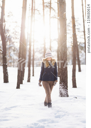 Happy young woman plays with a snow in sunny winter day. Girl enjoys winter, frosty day. 119680614