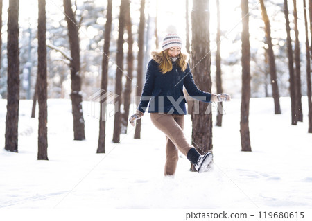 Happy woman plays with snow in sunny winter day. Girl enjoys winter, frosty day. Playing with snow. 119680615