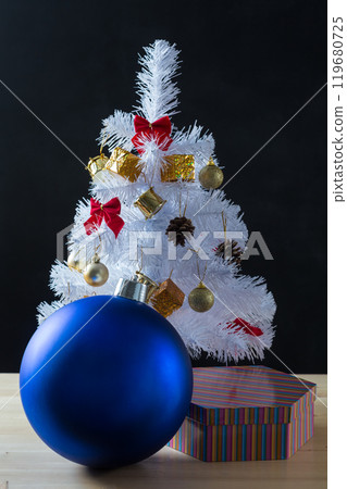 Small Christmas tree sitting on top of stool in a minimal room 119680725