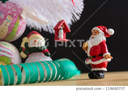 A small figurine of Santa Claus in a red and white suit holding a green sack 119680757
