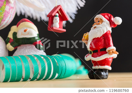 A small figurine of Santa Claus in a red and white suit holding a green sack, 119680760