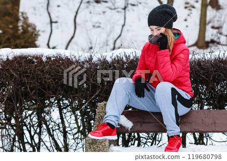 Woman wearing sportswear sitting outside during winter Woman wearing sportswear sitting outside during winter 119680798