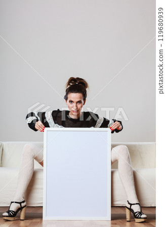 woman on sofa holding blank presentation board. woman on sofa holding blank presentation board. 119680939