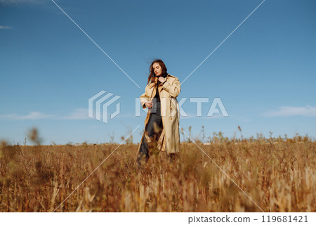 Young woman in stylish clothes posing in autumn field. Nature, fashion, lifestyle. Travel. 119681421