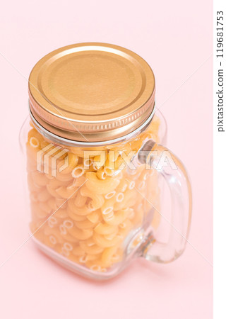 Uncooked Chifferi Rigati Pasta in Glass Jar on Pink Background Uncooked Chifferi Rigati Pasta in Glass Jar on Pink Background 119681753