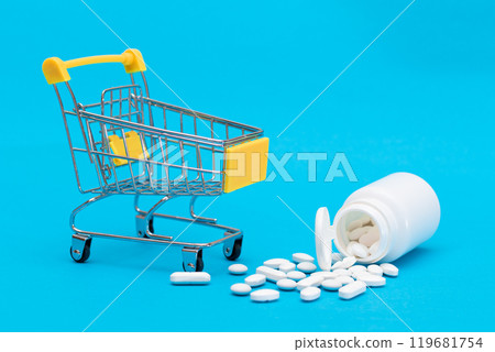 Scattered Pills or Capsules and Shopping Cart on Blue Background 119681754