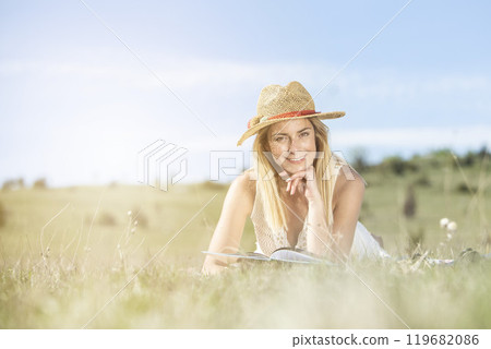 Young beautiful lady enjoying in nature park reading the book 119682086