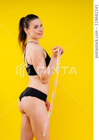 Weightloss, health and woman with measuring tape in a studio for her diet, exercise or wellness. Weightloss, health and woman with measuring tape in a studio for her diet, exercise or wellness. 119682141