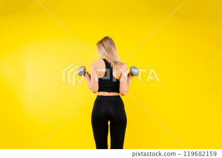 Muscular woman doing exercises with dumbbells at biceps. Photo of strong female isolated on studio Muscular woman doing exercises with dumbbells at biceps. Photo of strong female isolated on studio 119682159