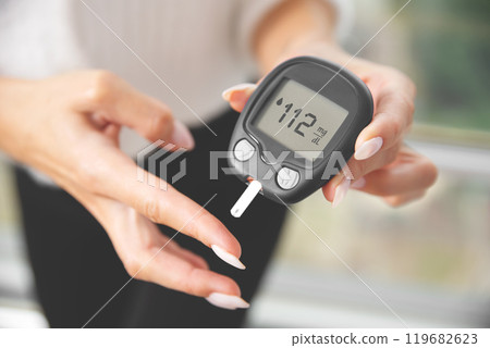 Woman is holding a blood glucose meter 119682623