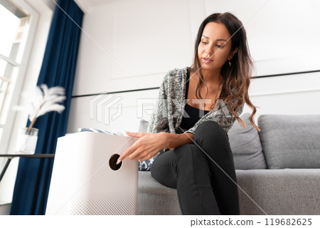 Woman using air purifier at home 119682625