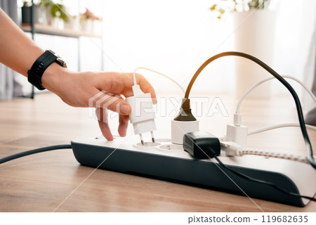 Person is plugging in a device to a power strip 119682635