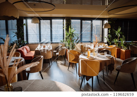 Stylish restaurant interior with natural light, cozy chairs and table setup, dining experience 119682659