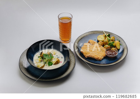 Complete lunch set with schnitzel, roasted potatoes, cold soup, and refreshing drink  119682685